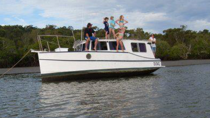 Four kids strike a pose on top of the boat with two adults