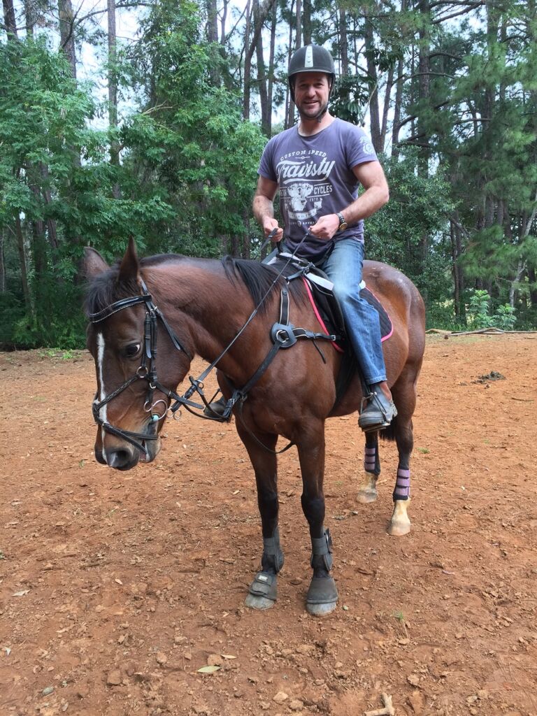 Byron on a horse wearing shirt and jeans