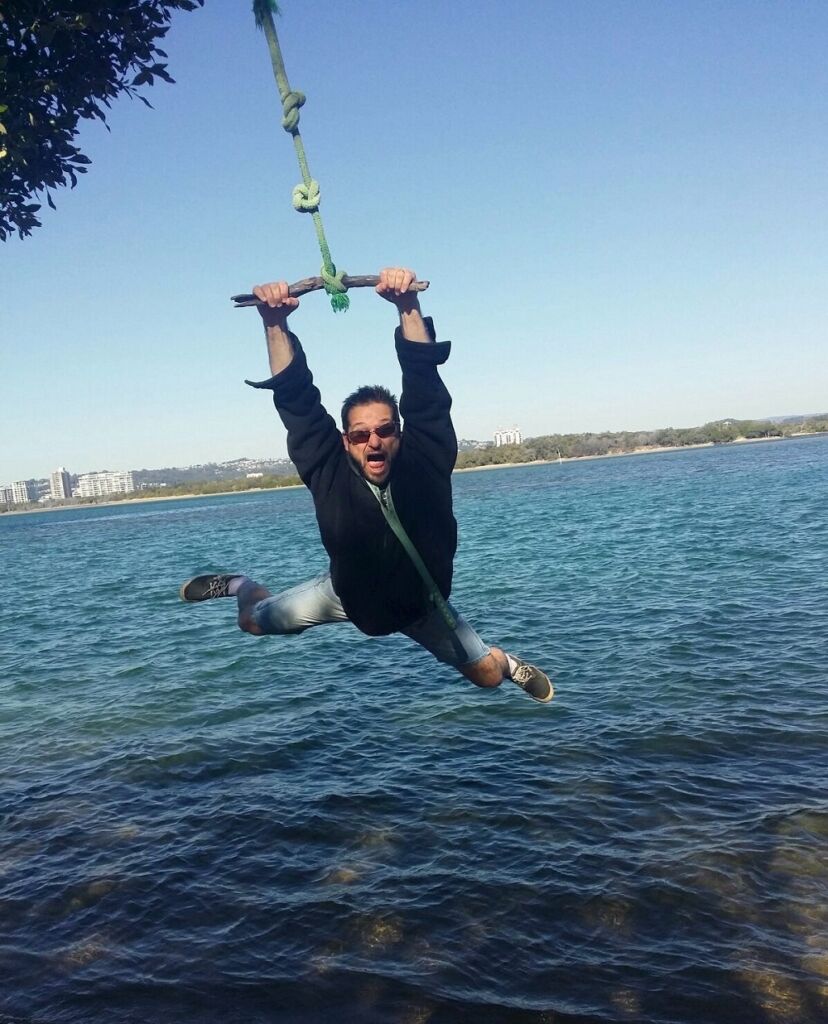 Byron swinging while holding onto a wooden bar tied to a rope
