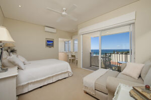 A photo of an elegant bedroom with a balcony that overlooks the ocean.