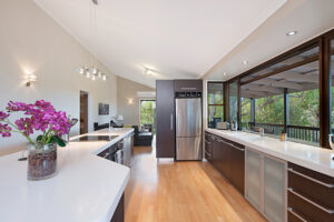 A contemporary kitchen with a sleek refrigerator, stylish sink, minimalist cabinets, smooth countertops, and bright lighting, offering a clean and organized cooking space.