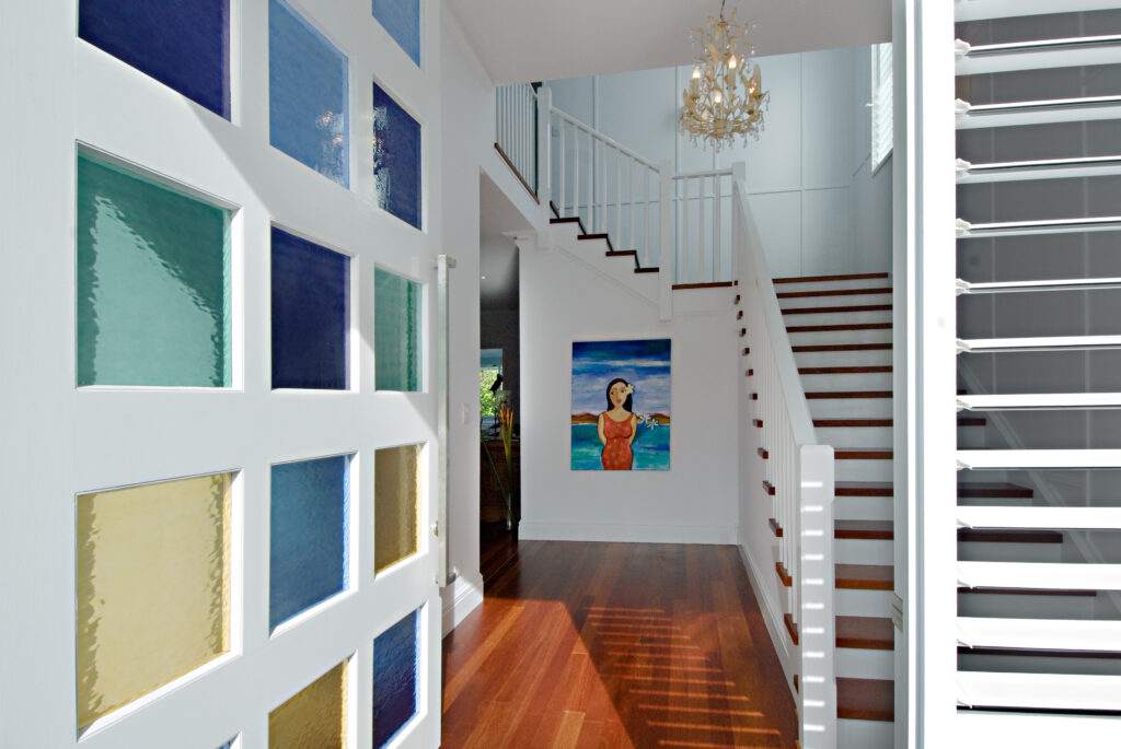 A well-lit hallway showcasing a stunning chandelier and an artistic painting on the wall