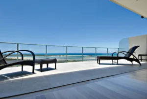 A sunny balcony on the Sunshine Coast area featuring chairs and a stunning view of the ocean.