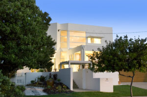 An image of the white house with a large tree in front, beautifully situated in the Sunshine Coast region.