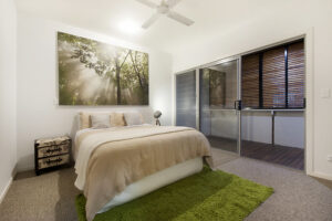 A spacious main bedroom on the residence of Sunshine Coast featuring a large bed and an elegant painting adorning the wall.