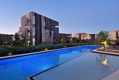 A contemporary swimming pool framed by a modern building, emphasizing a blend of architecture and relaxation