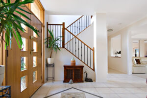 A bright white foyer featuring a staircase and a decorative plant, creating an inviting and elegant atmosphere.