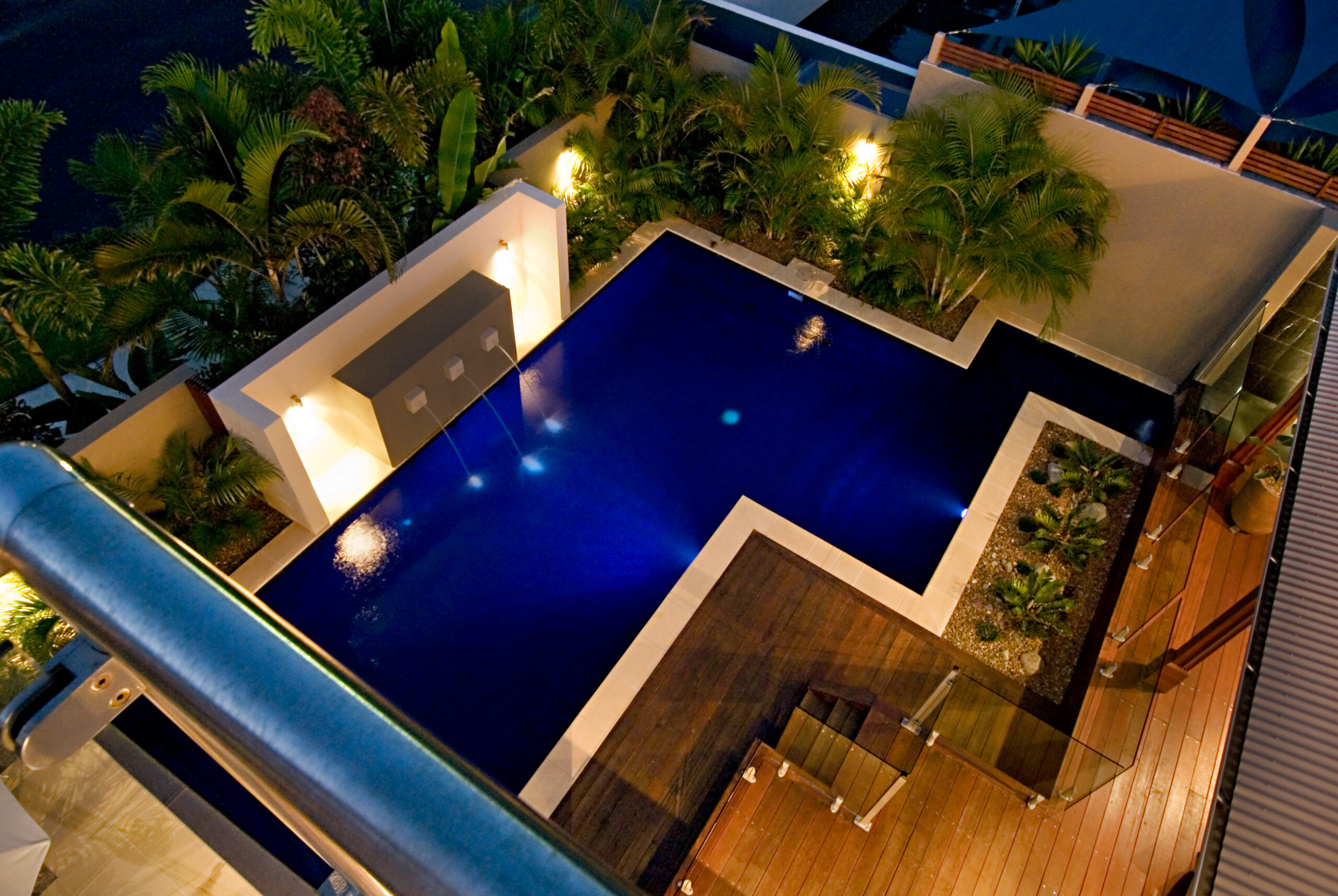 Aerial view of a pool surrounded by a deck and patio, showcasing a serene outdoor space for relaxation
