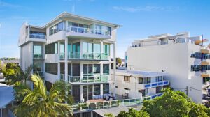 A sleek apartment building framed by tall palm trees, highlighting a blend of modern design and tropical landscaping.