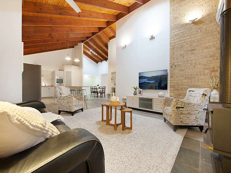 A cozy living room features a wooden ceiling in Sunshine Coast, creating an inviting atmosphere for relaxation.