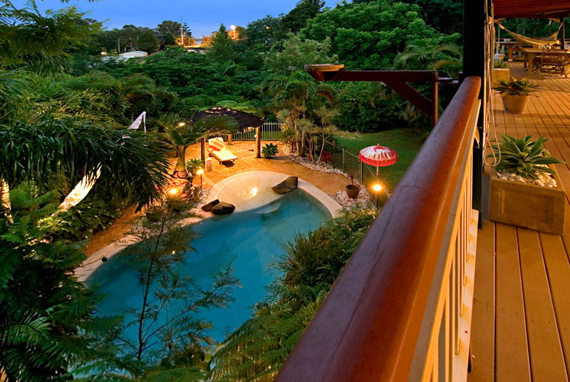 A scenic view of a pool and deck from the balcony in the area of Sunshine Coast, showcasing vibrant surroundings.